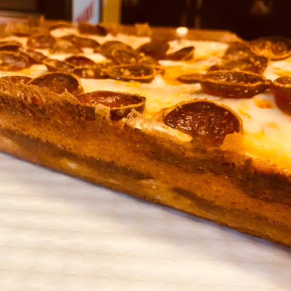 Close-up of a thick-crust pepperoni pizza slice from Biaggio Pizzeria, showcasing crispy edges and melted cheese.