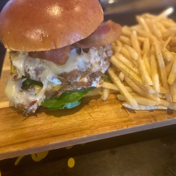 A juicy burger with melted cheese, bacon, and lettuce, served with a side of golden fries.