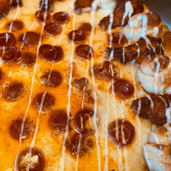 Close-up of a Biaggio Pizzeria pizza with pepperoni, chicken, and a white sauce drizzle.