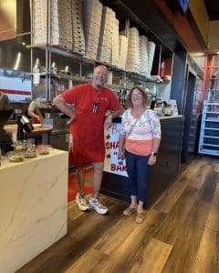 owner standing next to woman in pizza shop